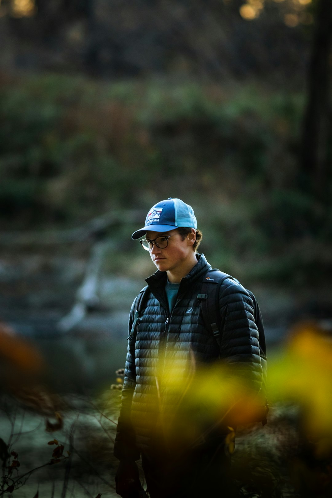 man in blue and black plaid dress shirt and blue fitted cap standing near river during