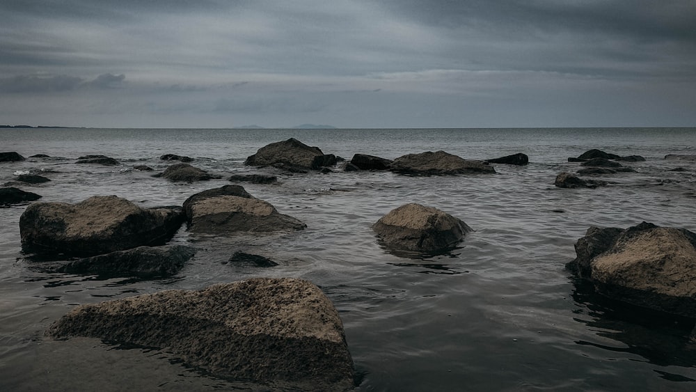 brown rock formation on sea under white clouds during daytime