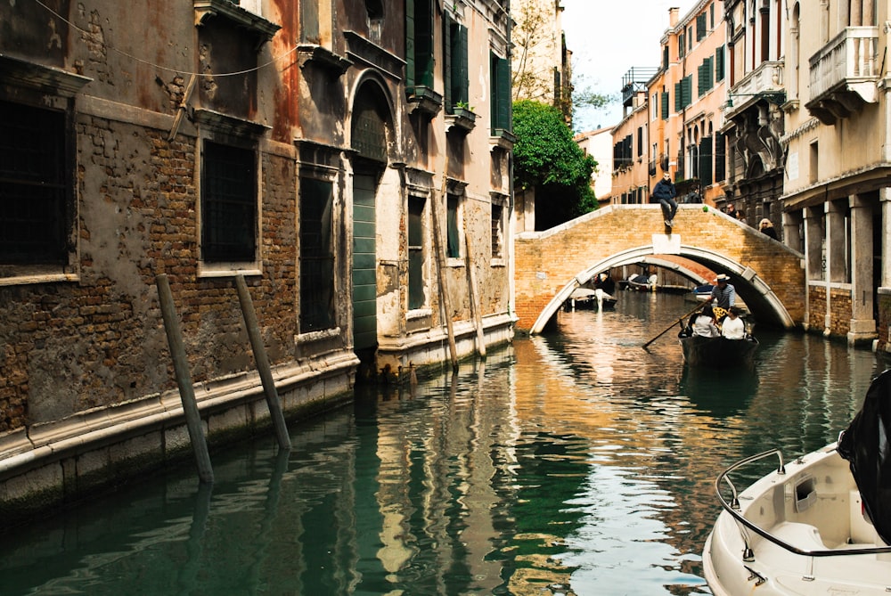 white boat on river between concrete buildings during daytime