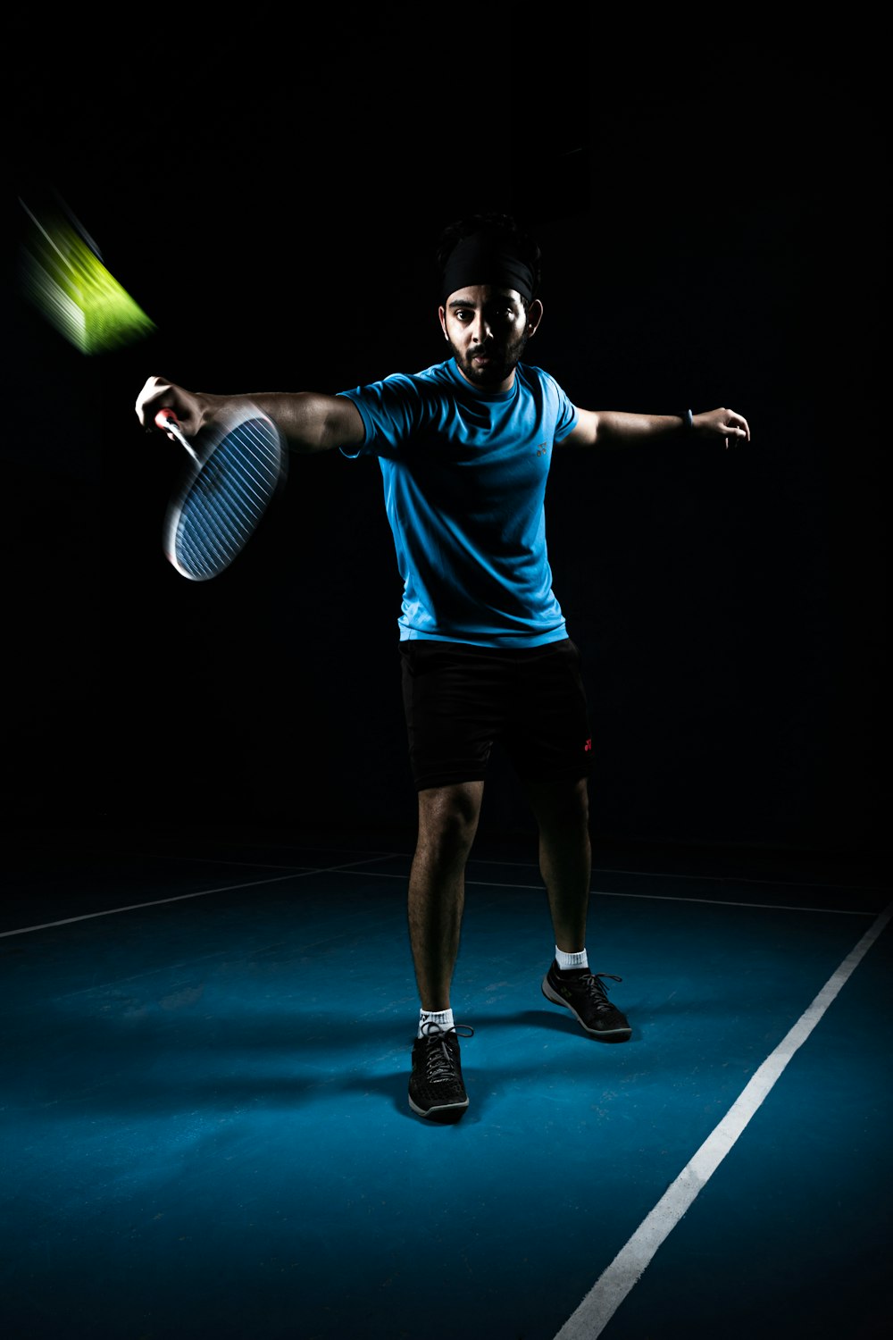 man in blue crew neck t-shirt and black shorts holding green tennis racket