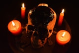 Close-up of a skull-embellished candle holder glowing softly in dim light.