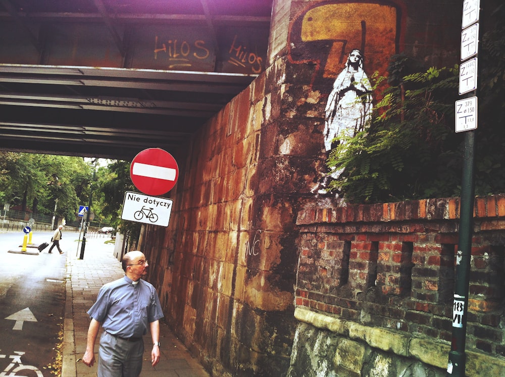 man in blue t-shirt standing beside red and white stop sign