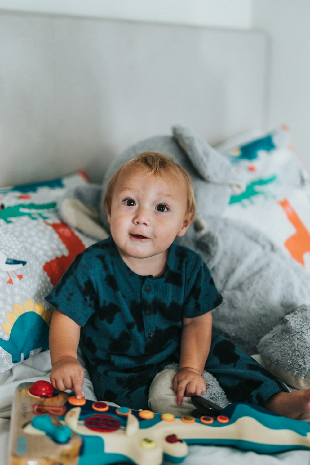 child in blue and red button up shirt sitting on bed