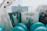 A festive arrangement featuring gift bags surrounded by blue balloons. One bag prominently displays a large number '1', embellished with playful animal illustrations, suggesting a first birthday celebration. The setup includes a cozy, furry blanket and decorative lights, adding a warm, inviting touch.