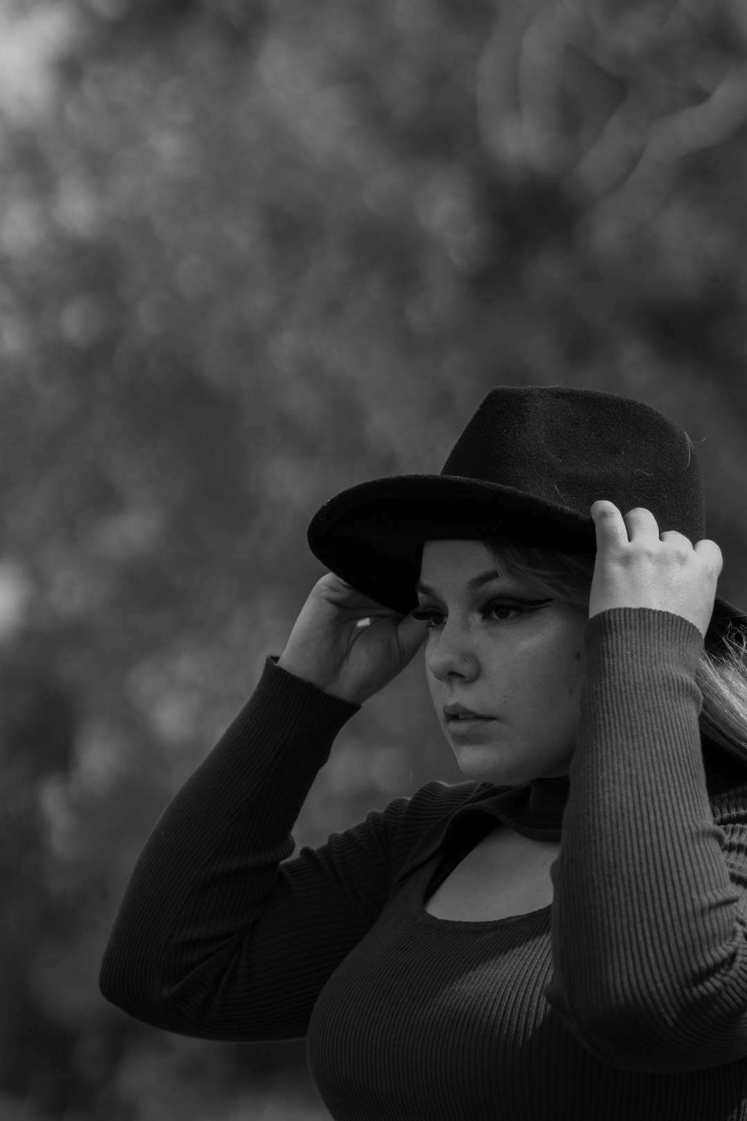 grayscale photo of woman in long sleeve shirt and black hat