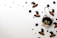 A whimsical composition featuring a black cat ornament with green eyes and a bow tie alongside assorted decorative black witch hats and googly eyes scattered on a white background.