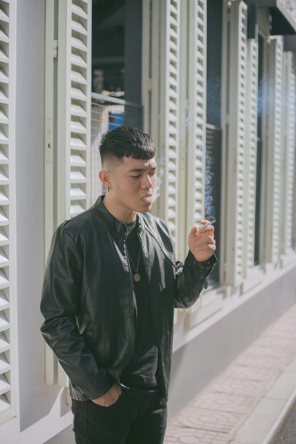 man in black leather jacket standing on white concrete stairs