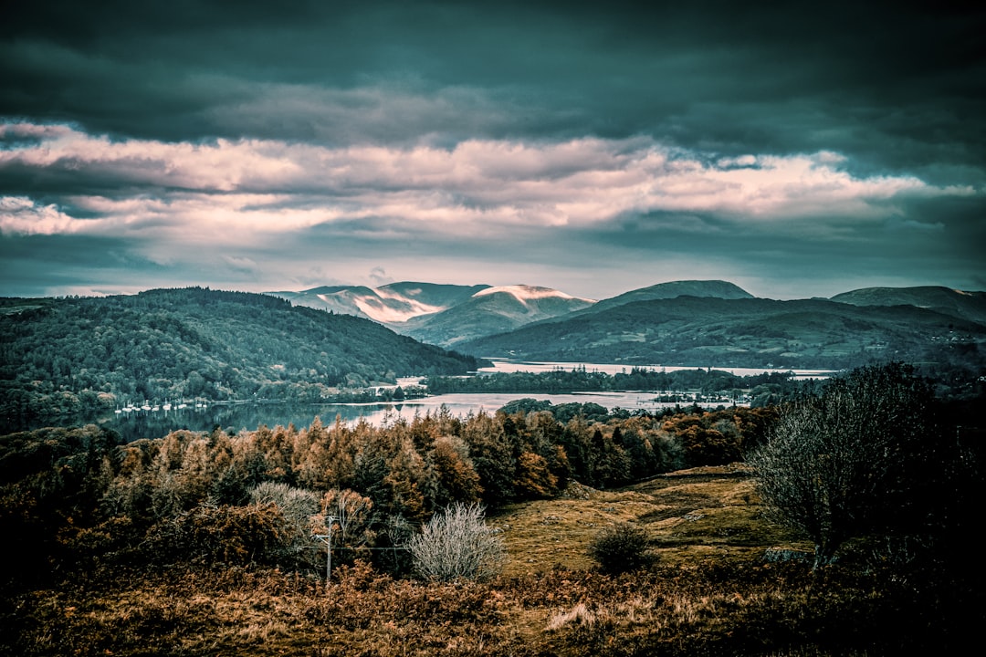 brown grass field near mountain under cloudy sky during daytime