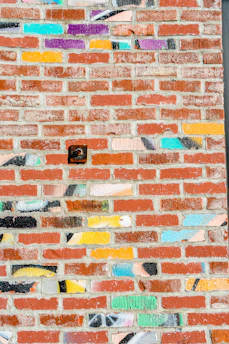 An outdoor brick wall with a colorful UV printed design shining under sunlight