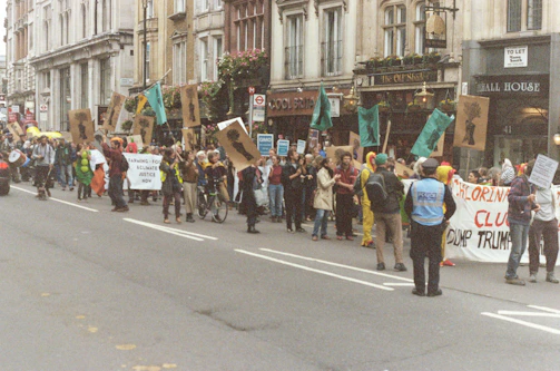 Union members wearing teal shirts marching together with banners in a neighborhood street.