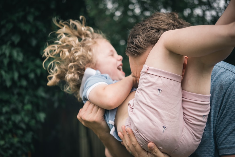 woman in pink sleeveless dress carrying baby in white shirt