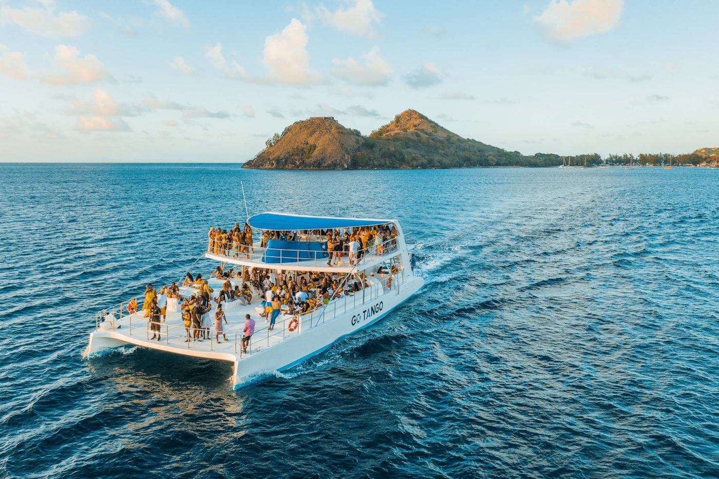 Catamaran full of guests sailing across turquoise Caribbean water