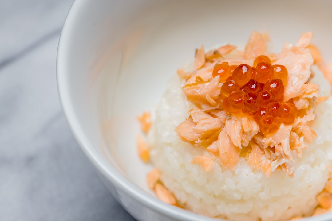 white rice with orange fruits in white ceramic bowl