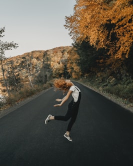 woman in white long sleeve shirt and black pants running on road during daytime