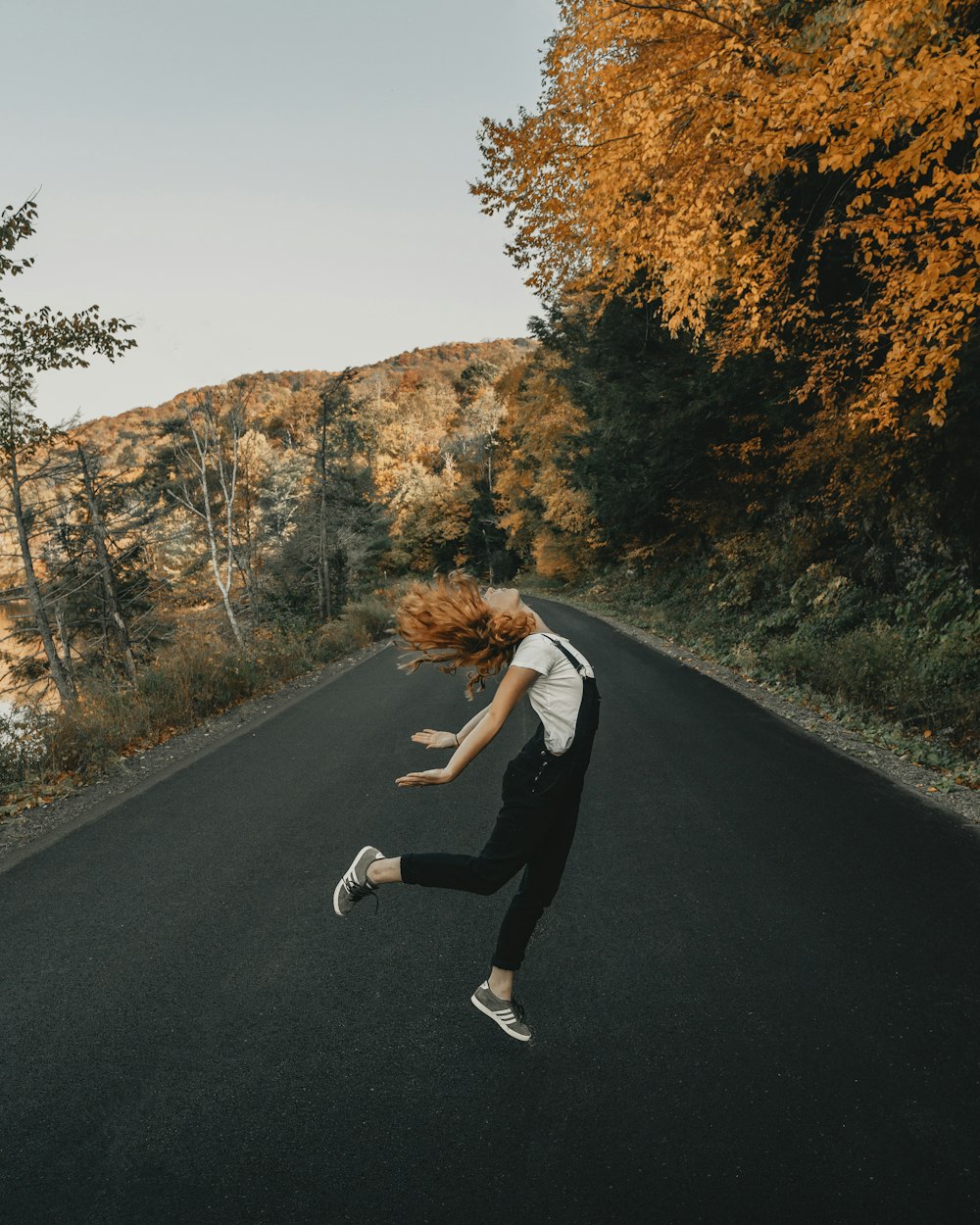 woman in white long sleeve shirt and black pants running on road during daytime