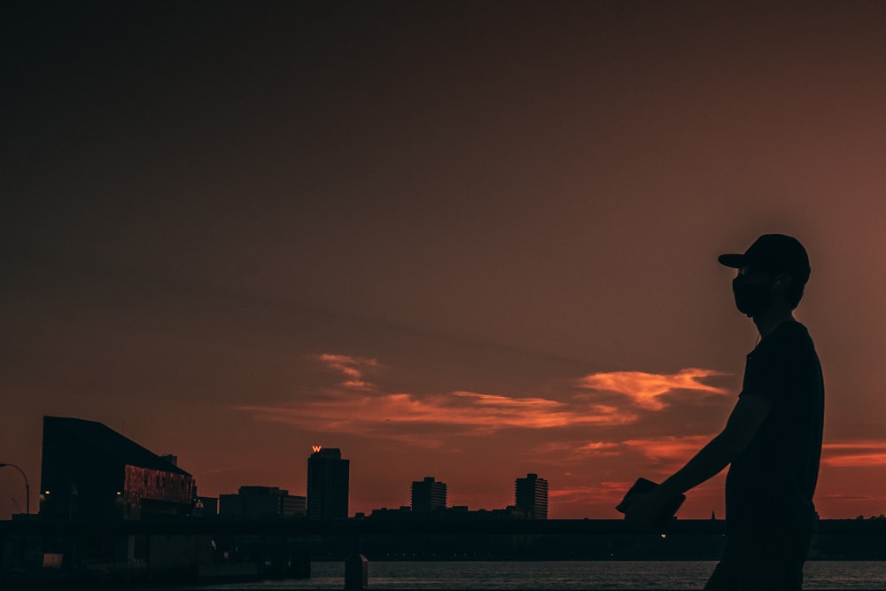 silhouette of man sitting on the edge of a building during sunset