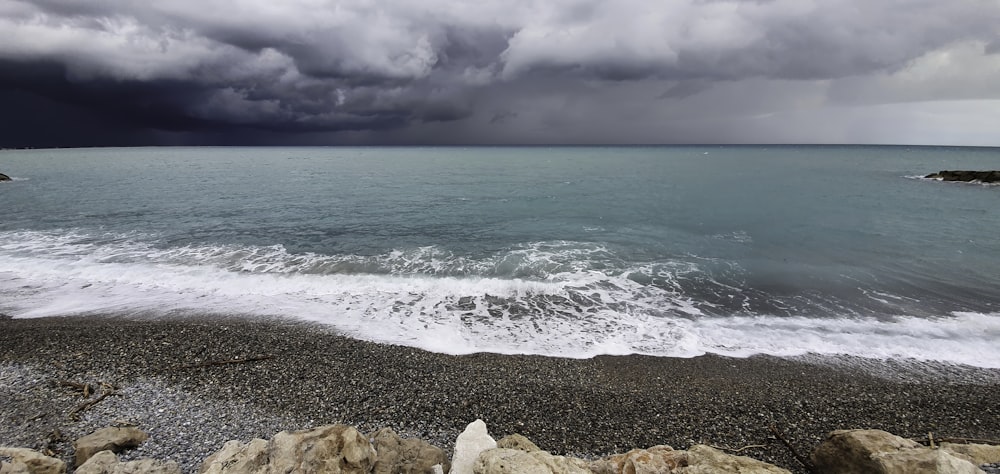 brown rocky shore under white clouds during daytime