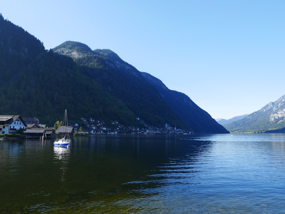 white boat on water near green mountain during daytime