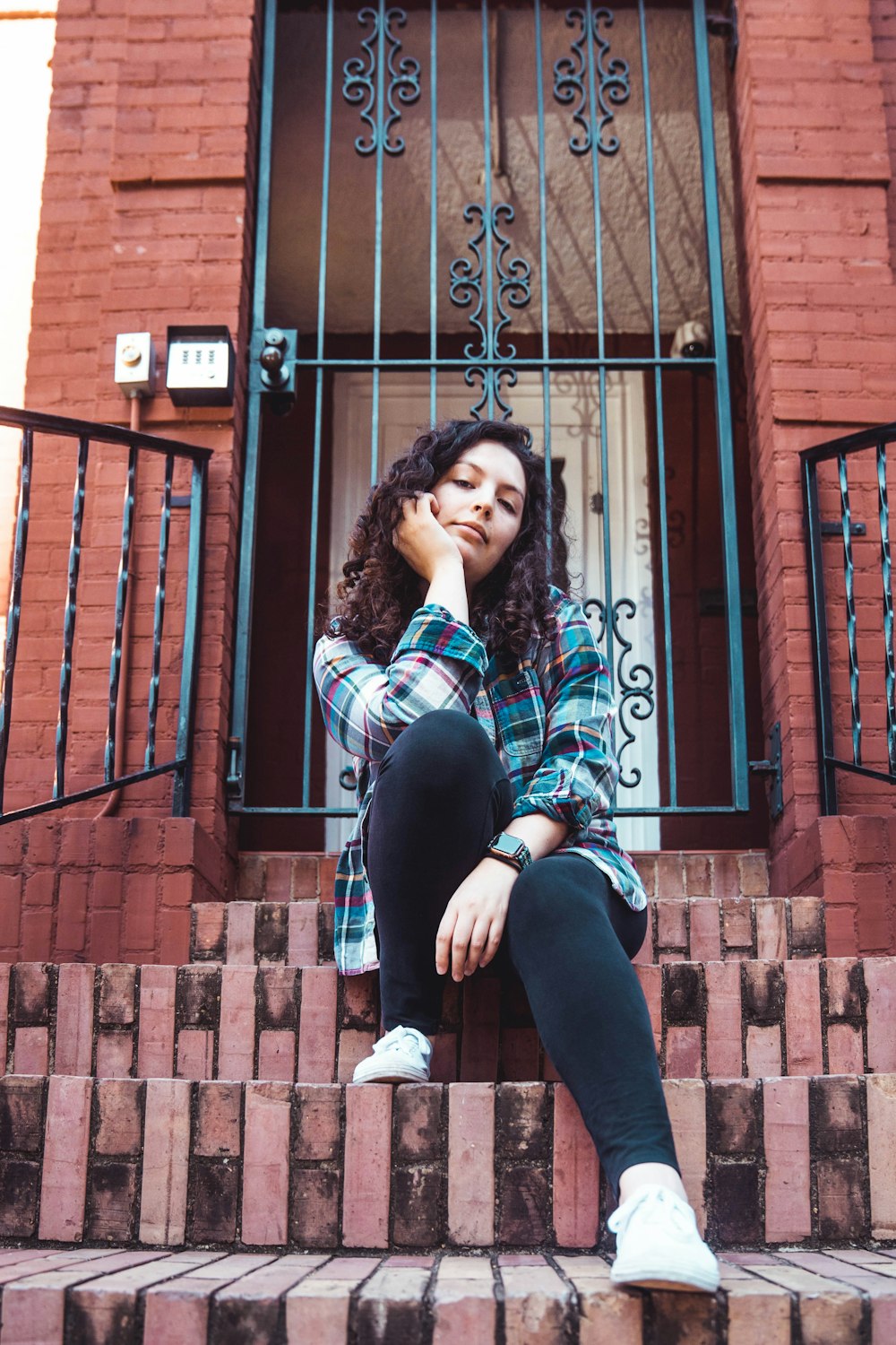 woman in black jacket and black pants sitting on brown brick wall during daytime