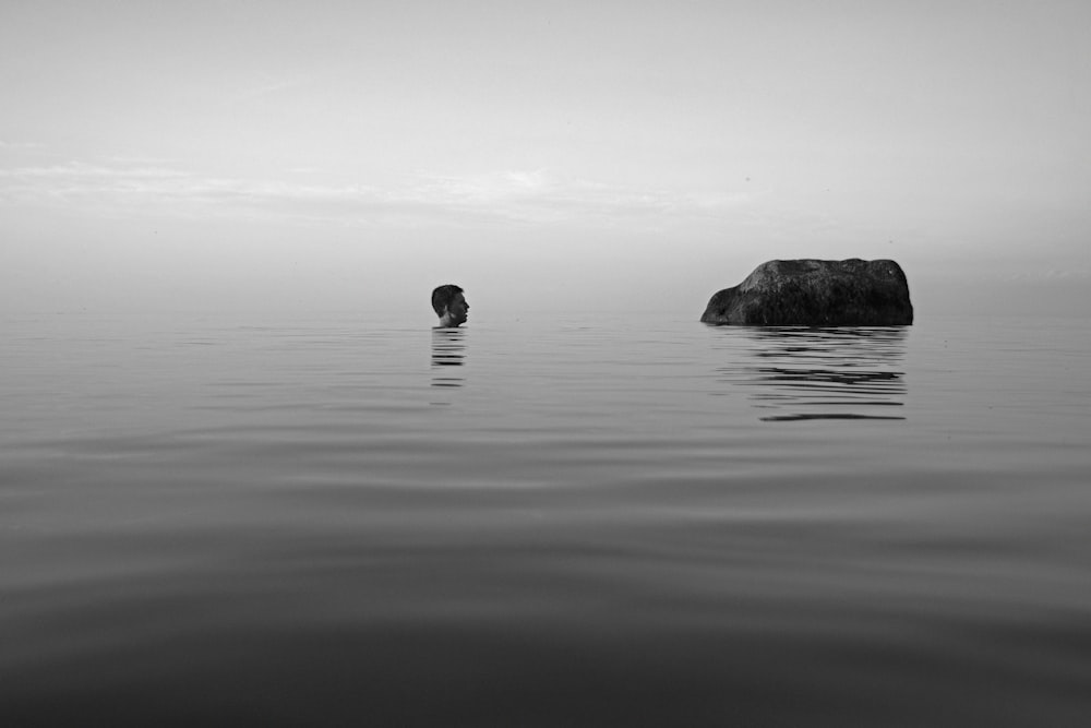 grayscale photo of rock formation on body of water