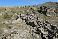 person in red and white shirt standing on rocky hill during daytime