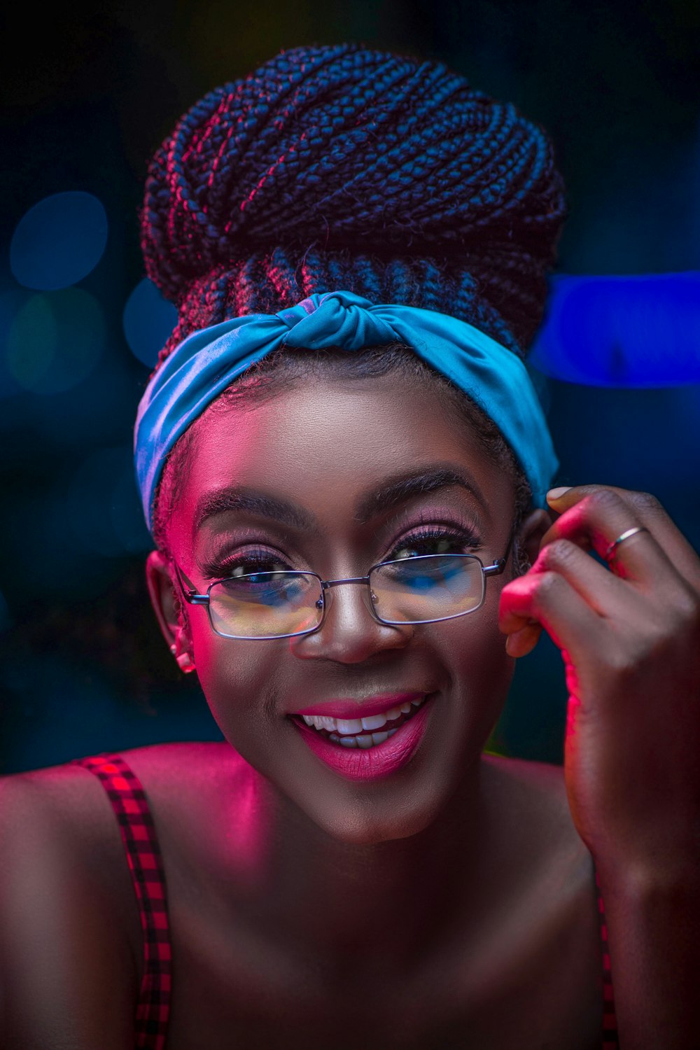 woman in pink tank top wearing blue and red knit cap and blue framed eyeglasses