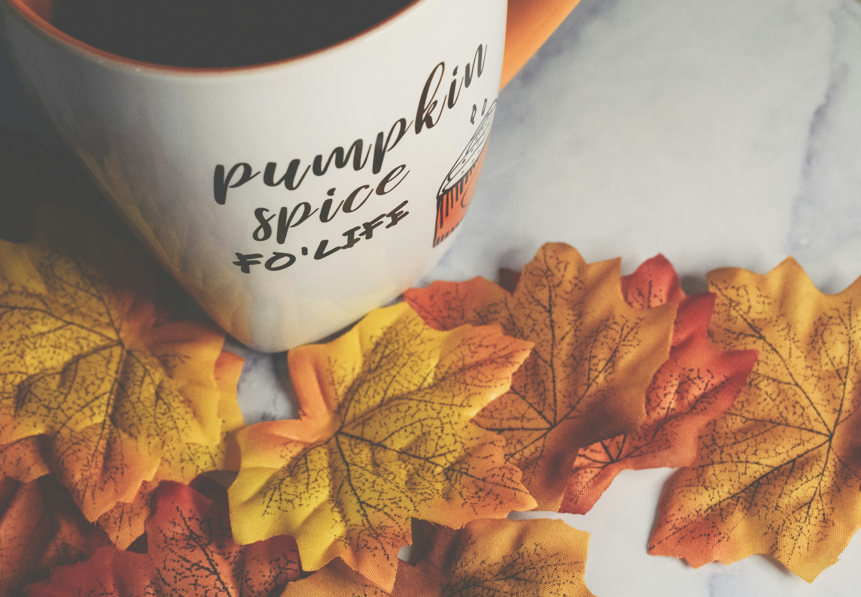 Pumpkin spice latte surrounded by autumn leaves