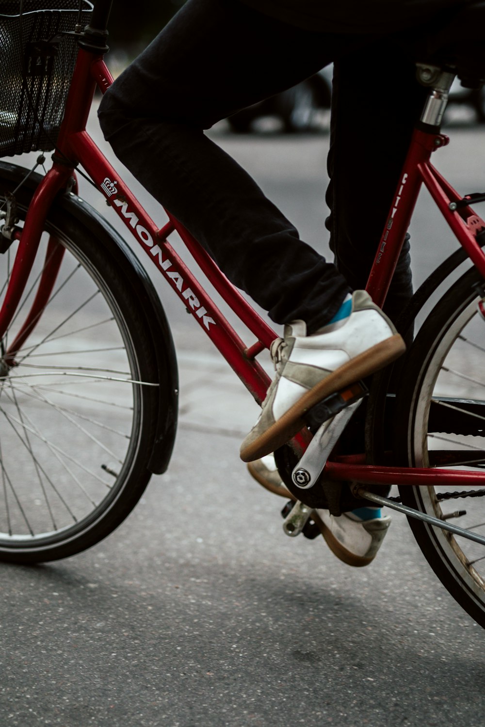 person in black pants riding red bicycle on road during daytime