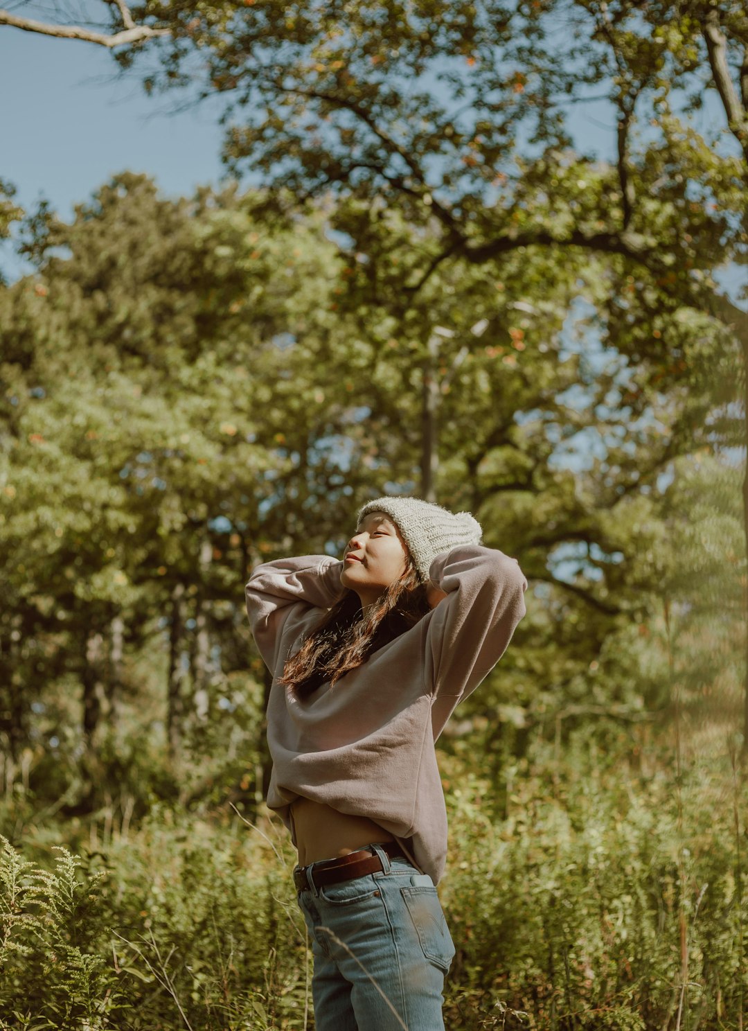 woman in brown jacket and brown pants standing on green grass field during daytime