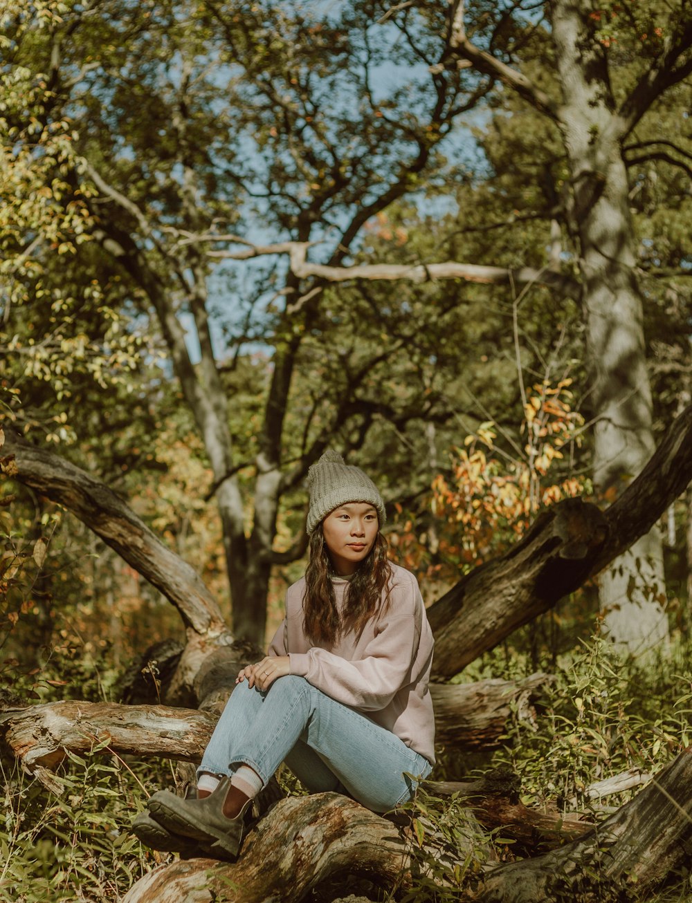 woman in gray knit cap sitting on tree log