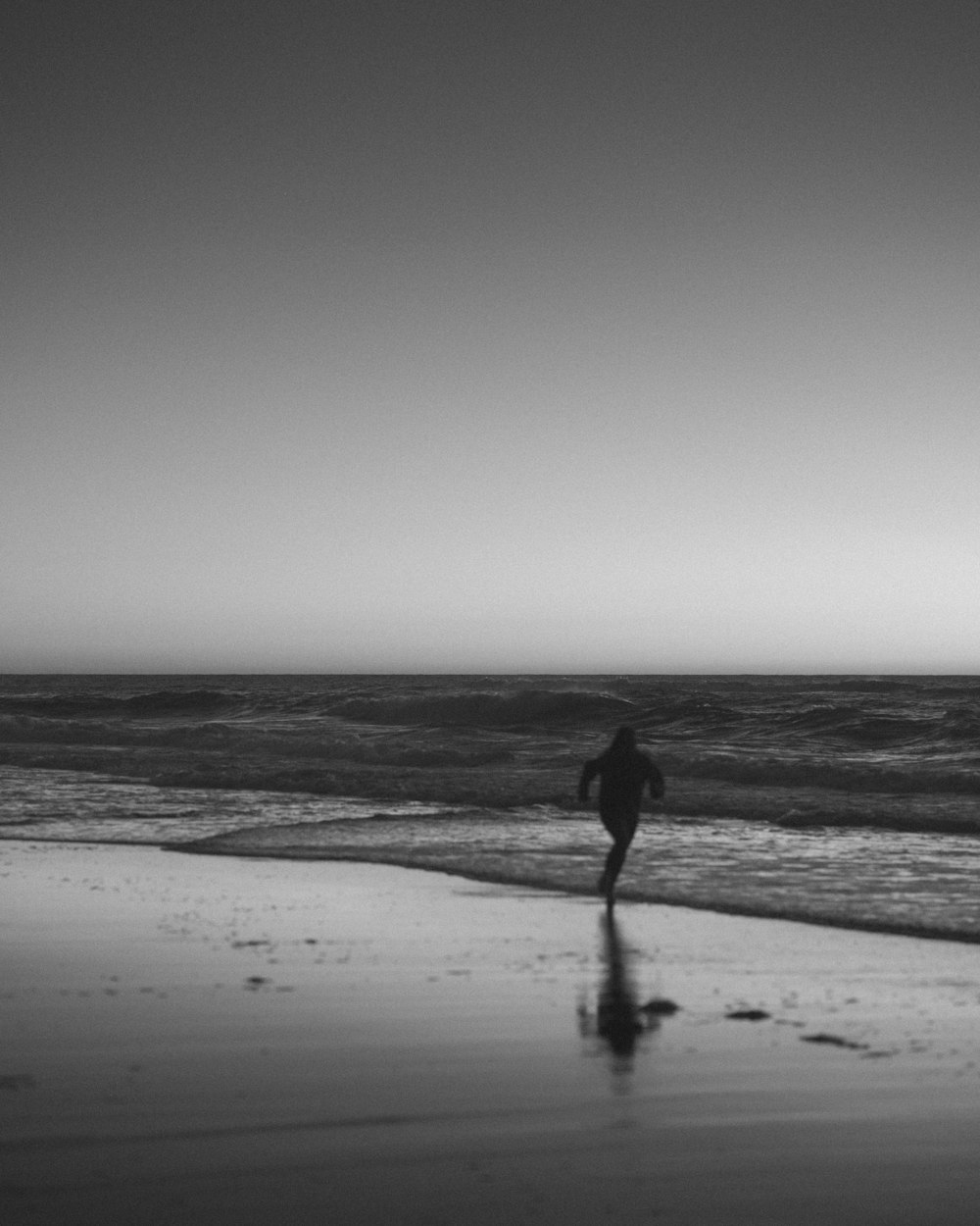 Silhouette der Person, die tagsüber am Strand spazieren geht