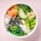 A bowl featuring a colorful assortment of fresh ingredients. There are thick slices of raw salmon, white rice topped with black sesame seeds, vibrant green edamame beans, thinly sliced cucumber, and seaweed strips. The bowl also contains creamy sauce, ginger slices, and a sprinkle of microgreens.