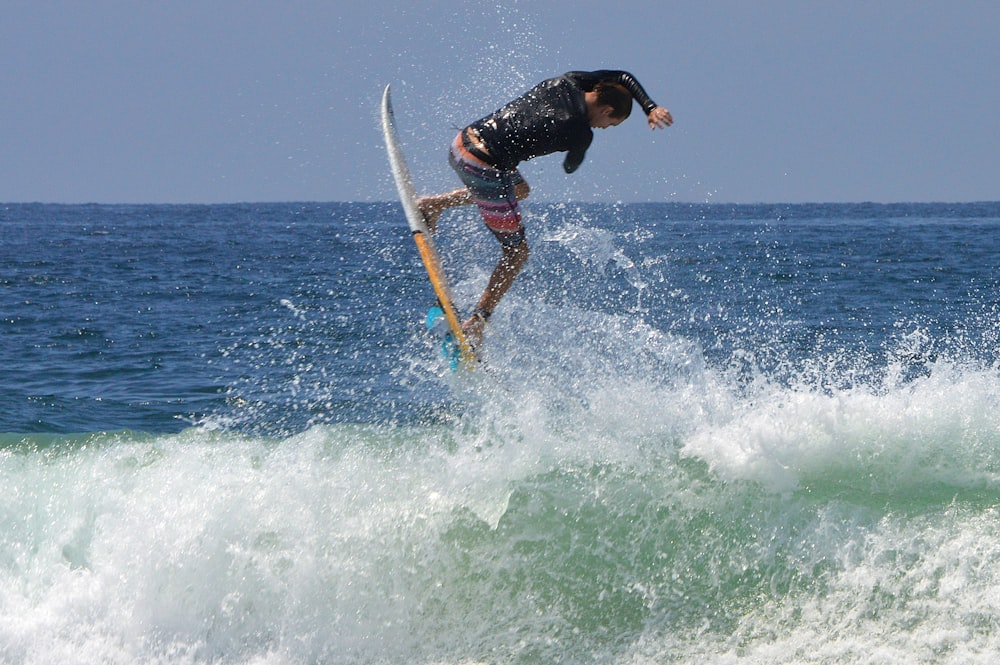 man in black wetsuit surfing on sea waves during daytime