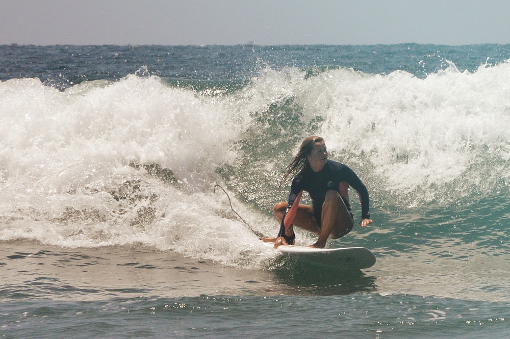 man in black wet suit surfing on sea waves during daytime