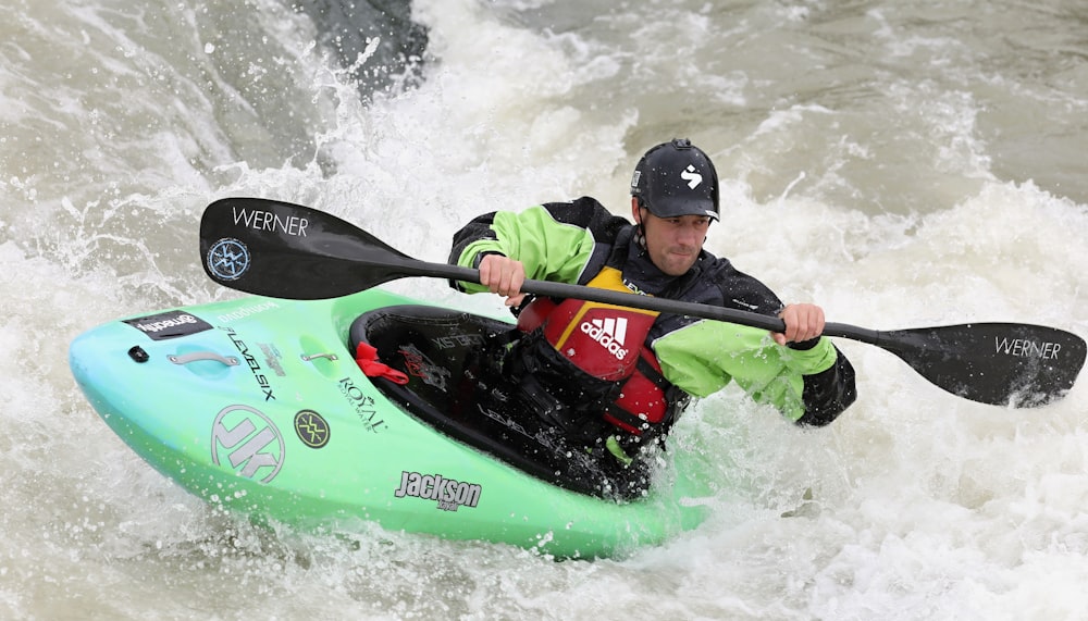 man in red and black jacket riding green kayak on water