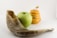 A shofar, a green apple, and a honey jar with a bee figurine on top are arranged against a plain background.