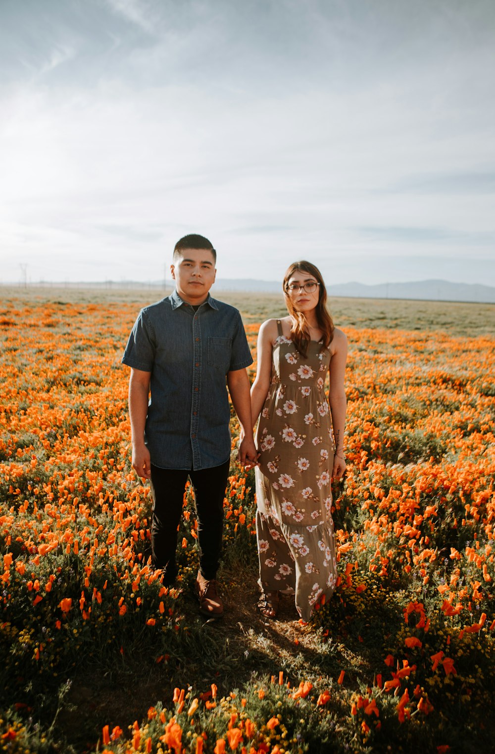 man and woman standing on flower field during daytime