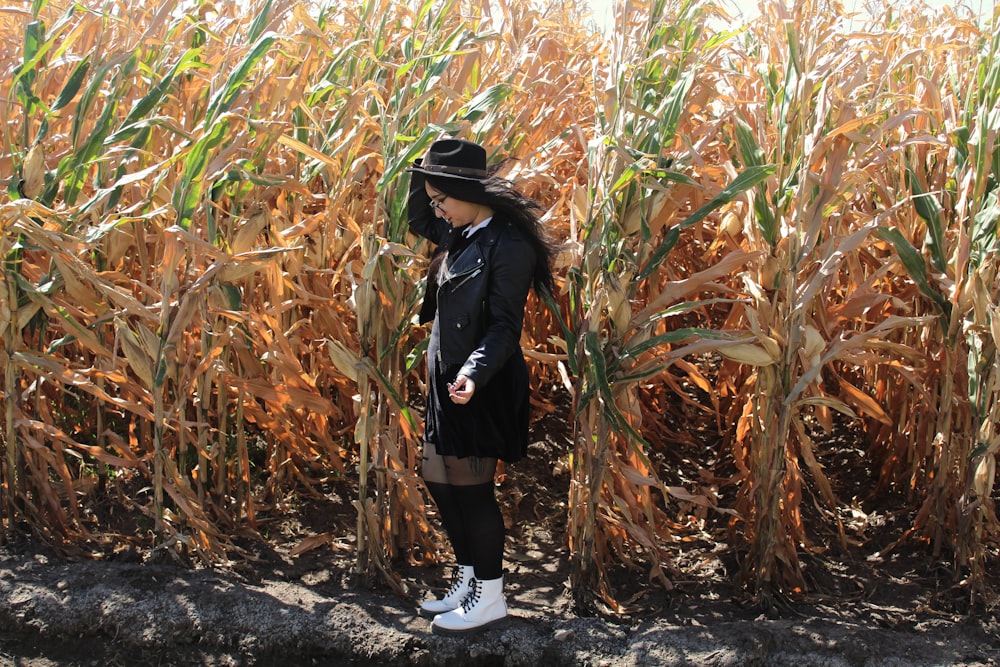 woman in black jacket and white pants standing on brown dried leaves during daytime