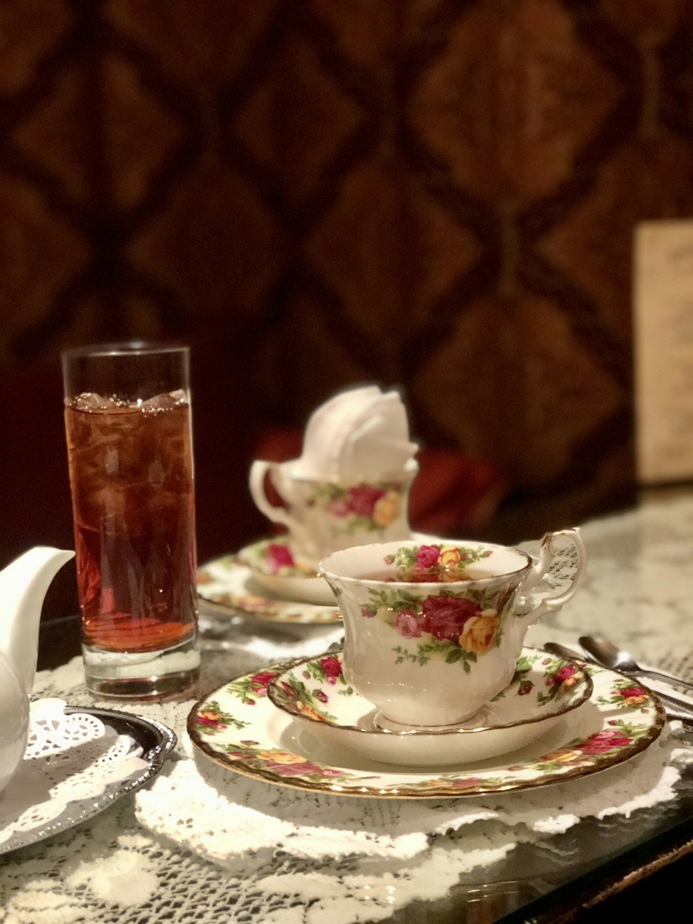 clear drinking glass on white floral ceramic saucer