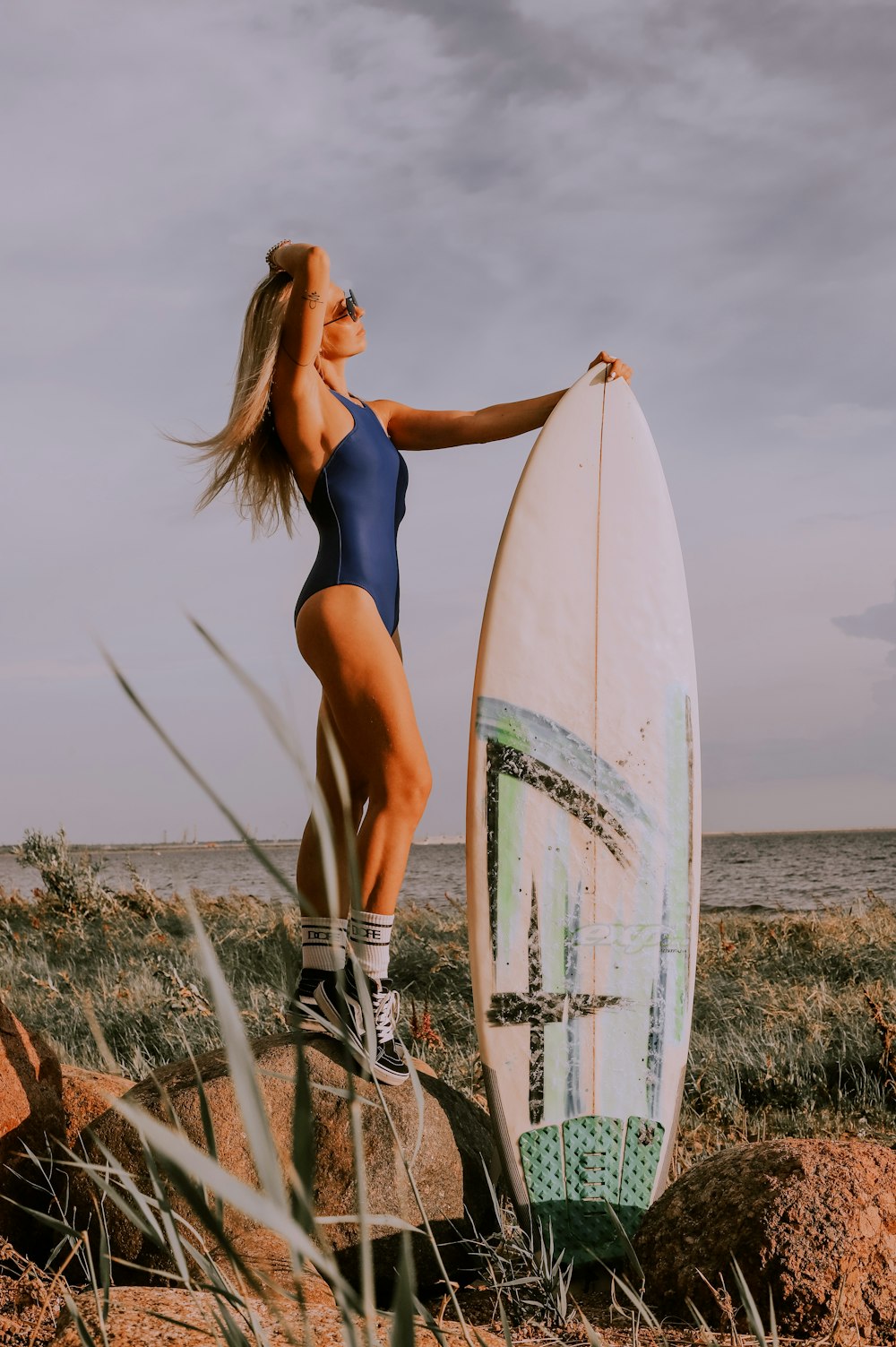 woman in blue one piece swimsuit holding white surfboard during daytime