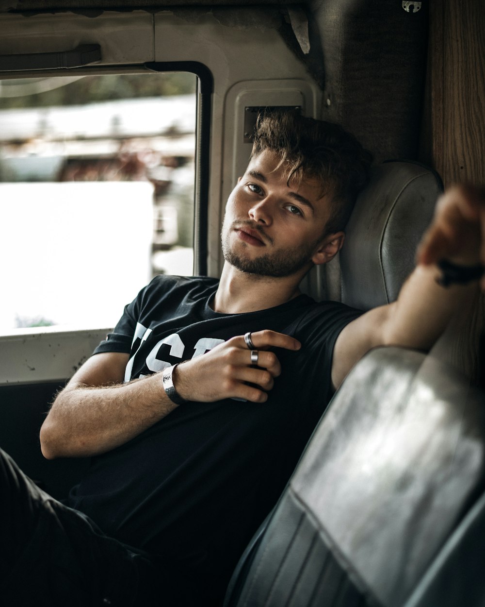 man in black crew neck t-shirt sitting on car seat