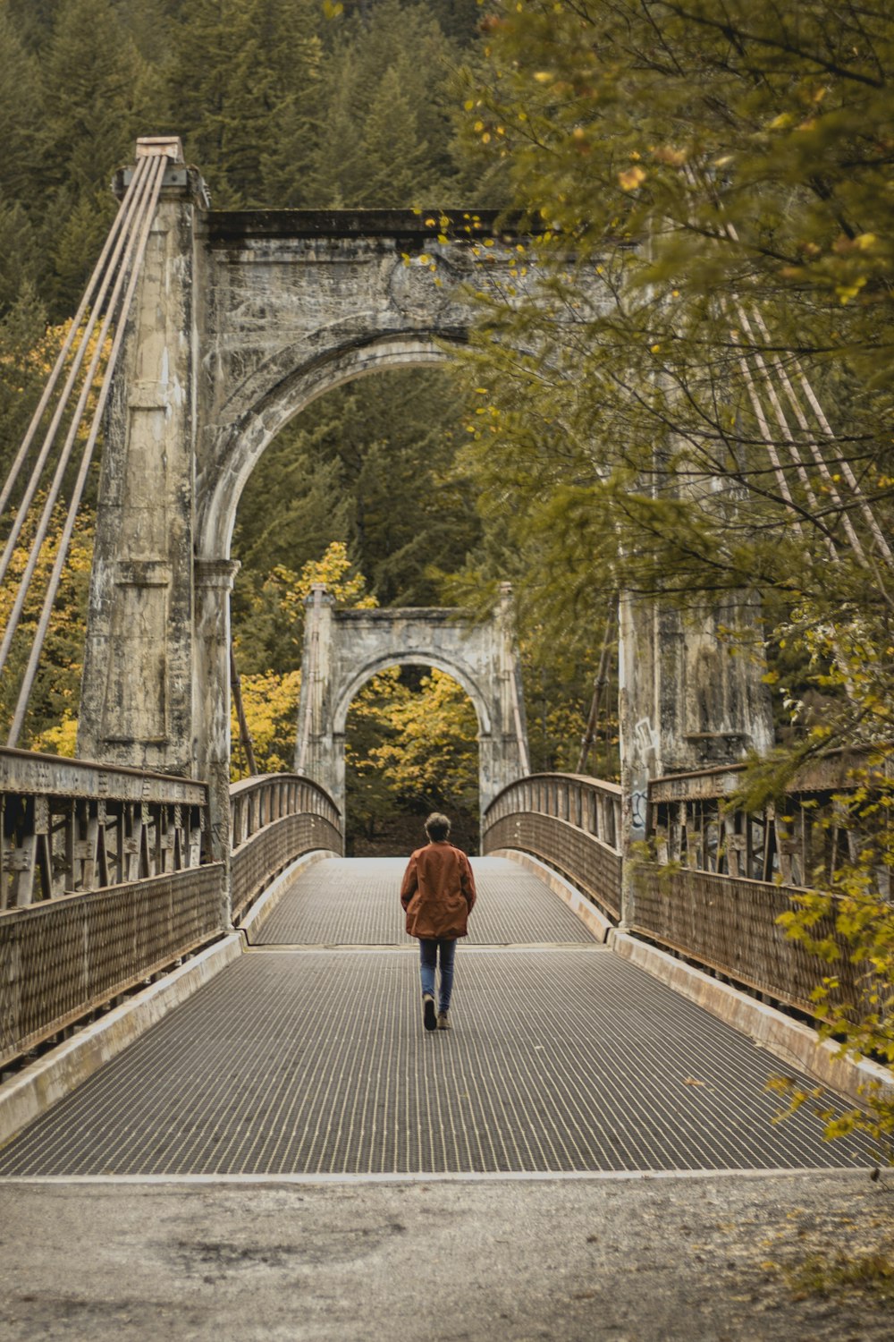 woman in red jacket and black pants walking on bridge