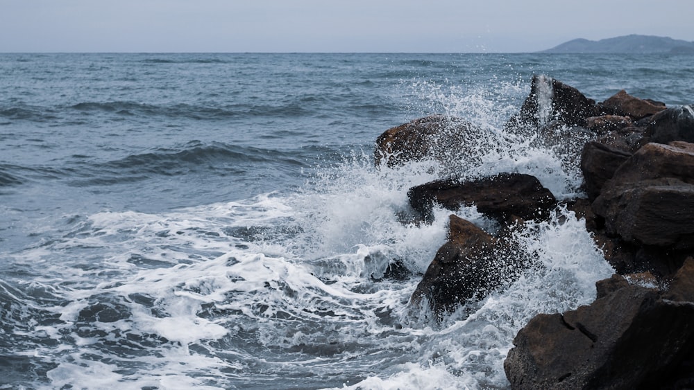 Meereswellen, die tagsüber auf braune Felsformationen stürzen