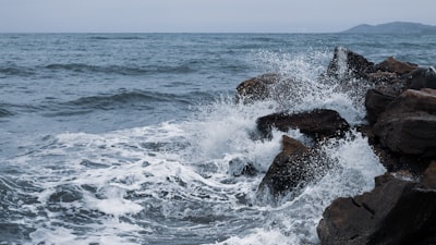 ocean waves crashing on brown rock formation during daytime zihuatanejo google meet background
