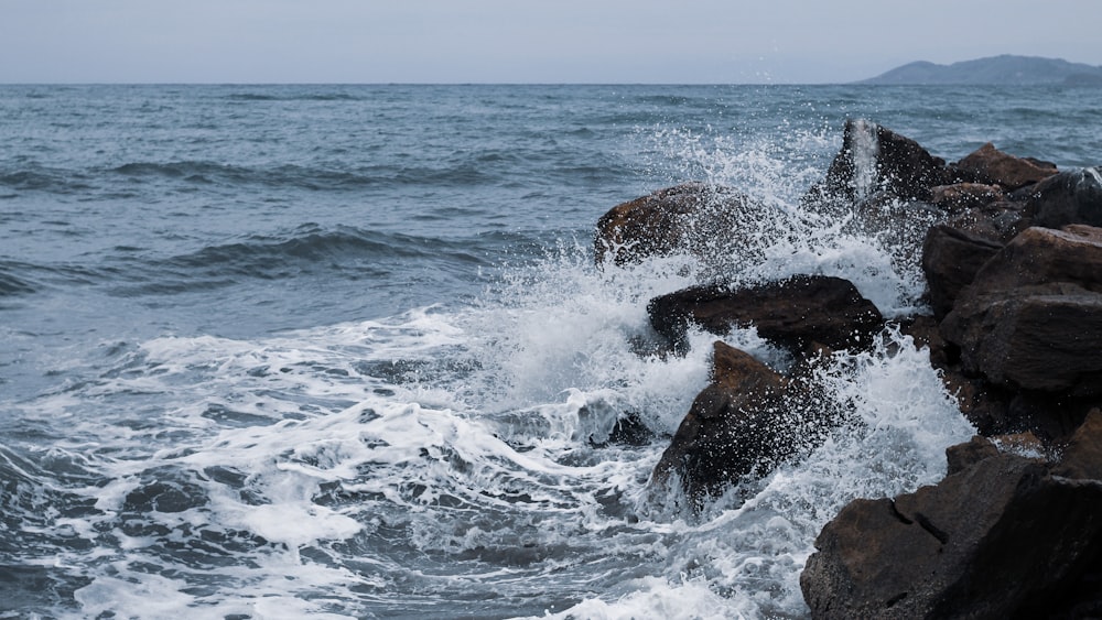 Onde dell'oceano che si infrangono sulla formazione rocciosa marrone durante il giorno