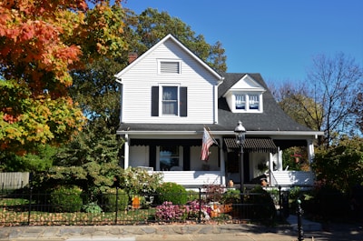 white and gray wooden house near green trees under blue sky during daytime