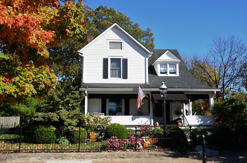 white and gray wooden house near green trees under blue sky during daytime