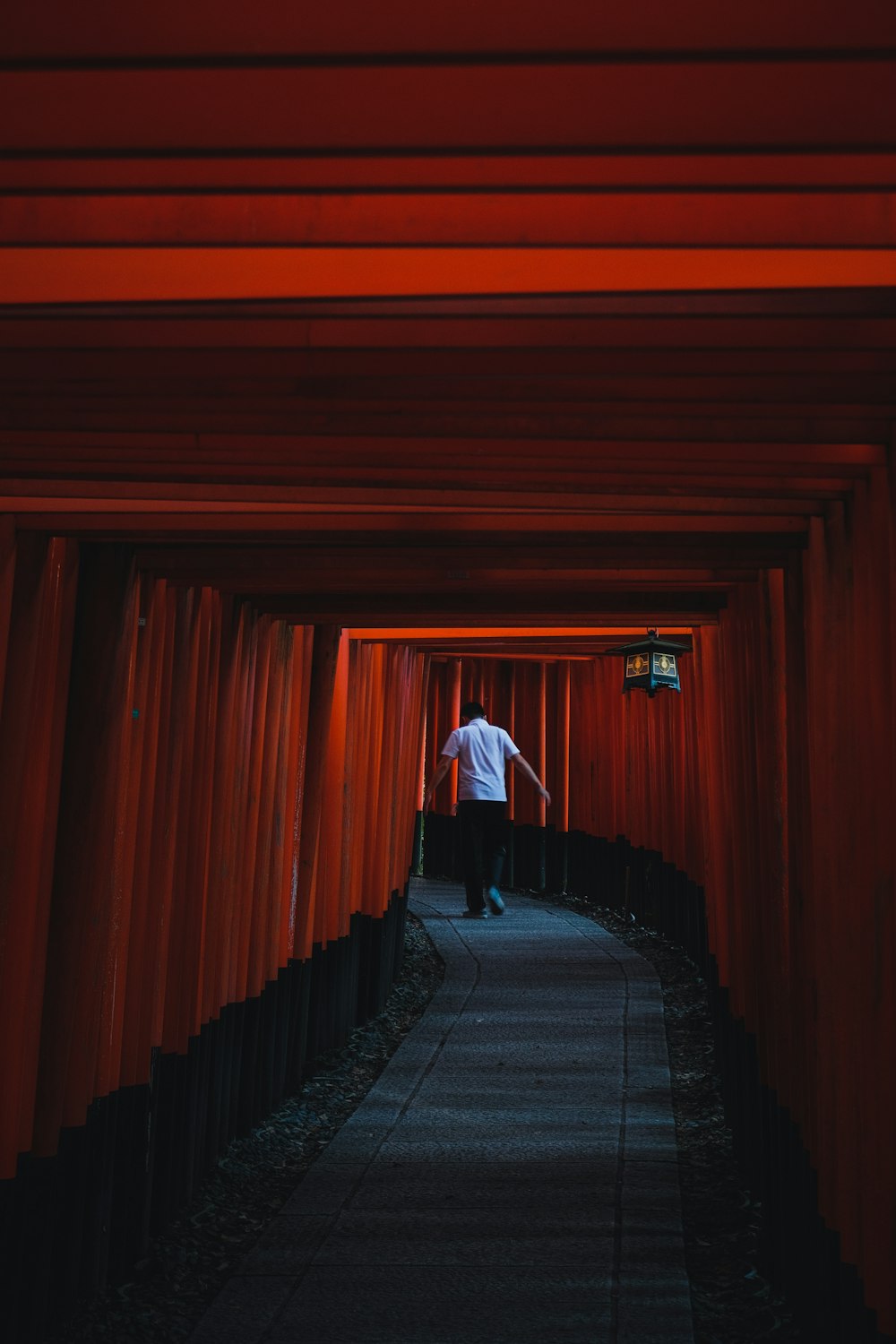 person in white long sleeve shirt and black pants walking on red tunnel
