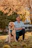 man in blue dress shirt sitting beside brown dog during daytime