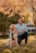 man in blue dress shirt sitting beside brown dog during daytime